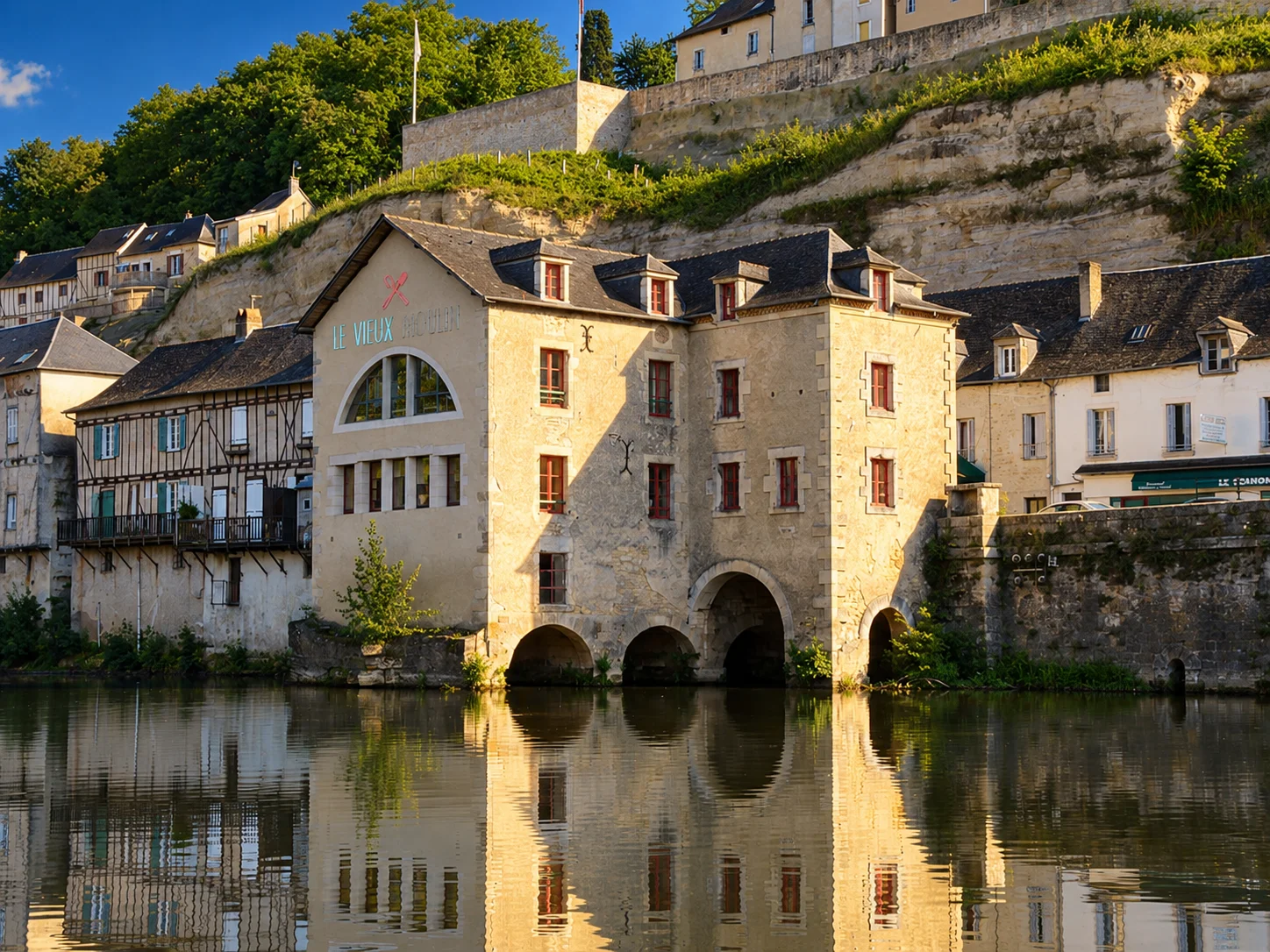 The old mill beside the Vézère in Terrasson stands below limestone cliffs and hillside houses.