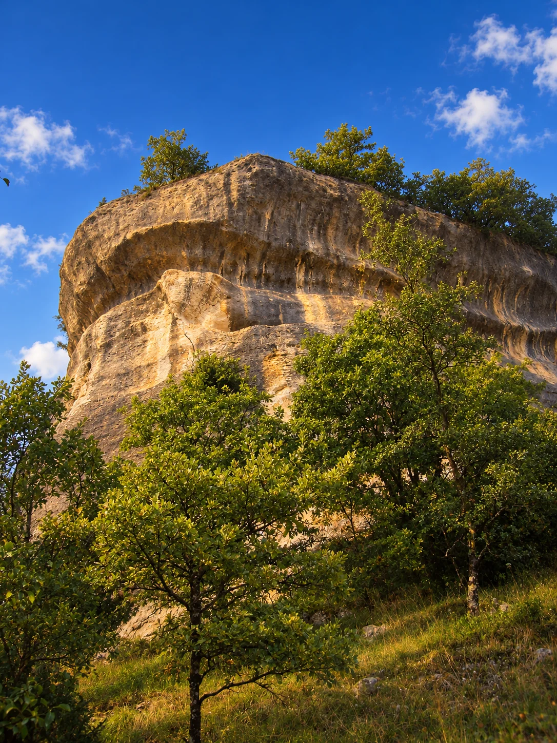 Font-de-Gaume cave, re-rendered from an openly licensed photo (Summer · Deep brochure blue · Golden hour)