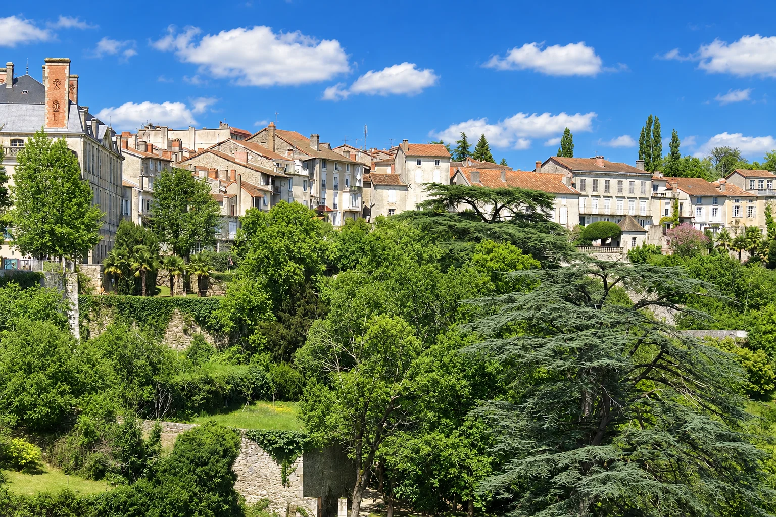 Houses in Nontron stand above terraced gardens and mature trees on the hillside.