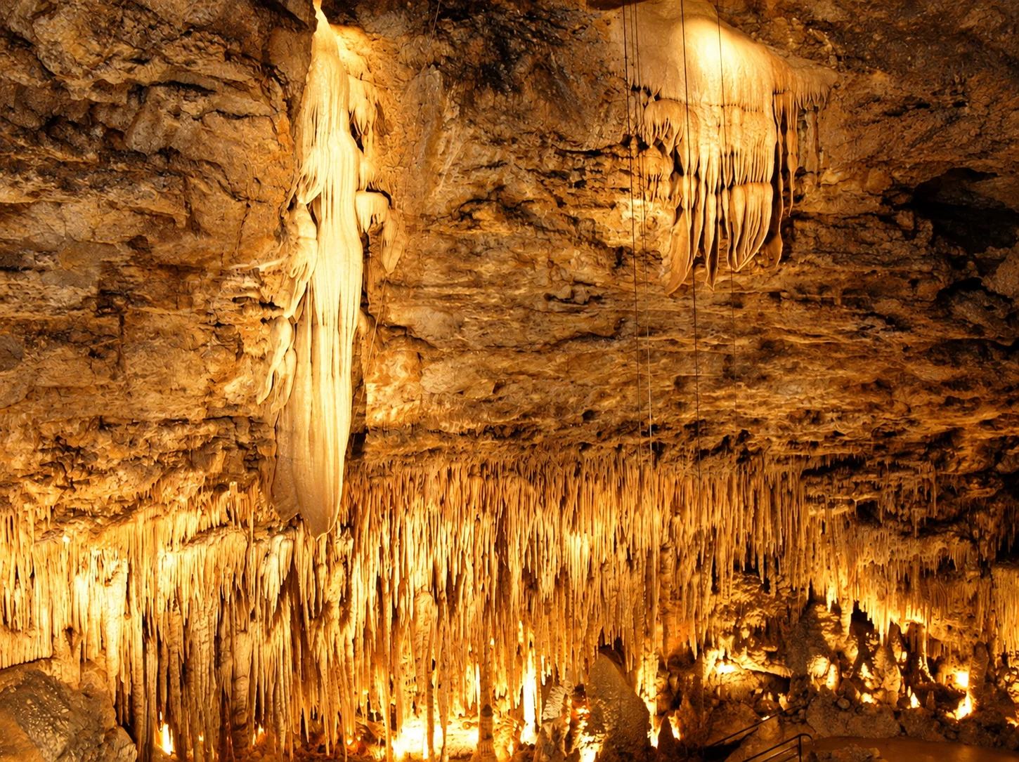 Large calcite draperies and rows of slender stalactites cover the cavern walls at the Gouffre de Proumeyssac.