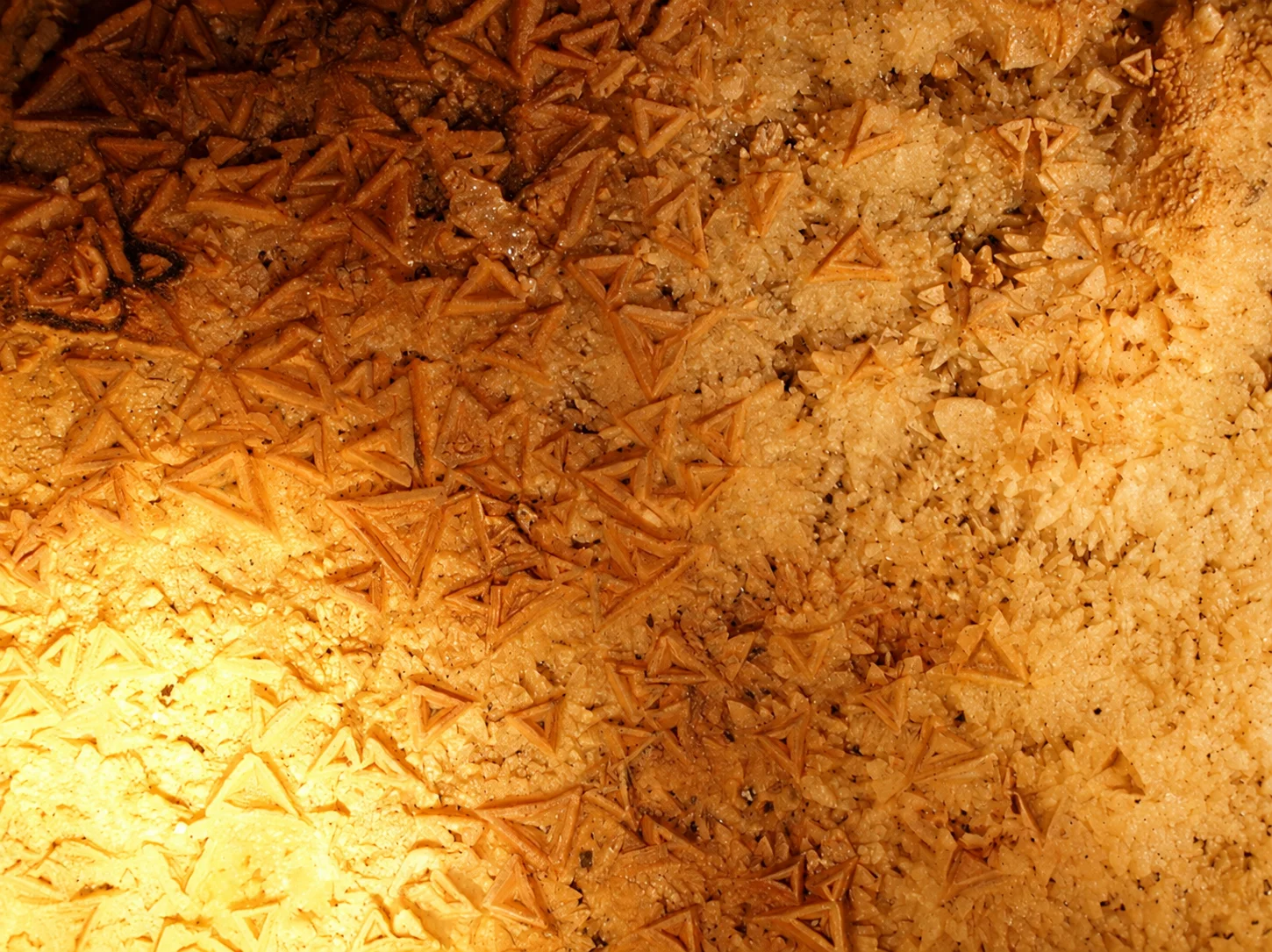 A close-up shows angular mineral crystals under artificial lighting inside the Gouffre de Proumeyssac.