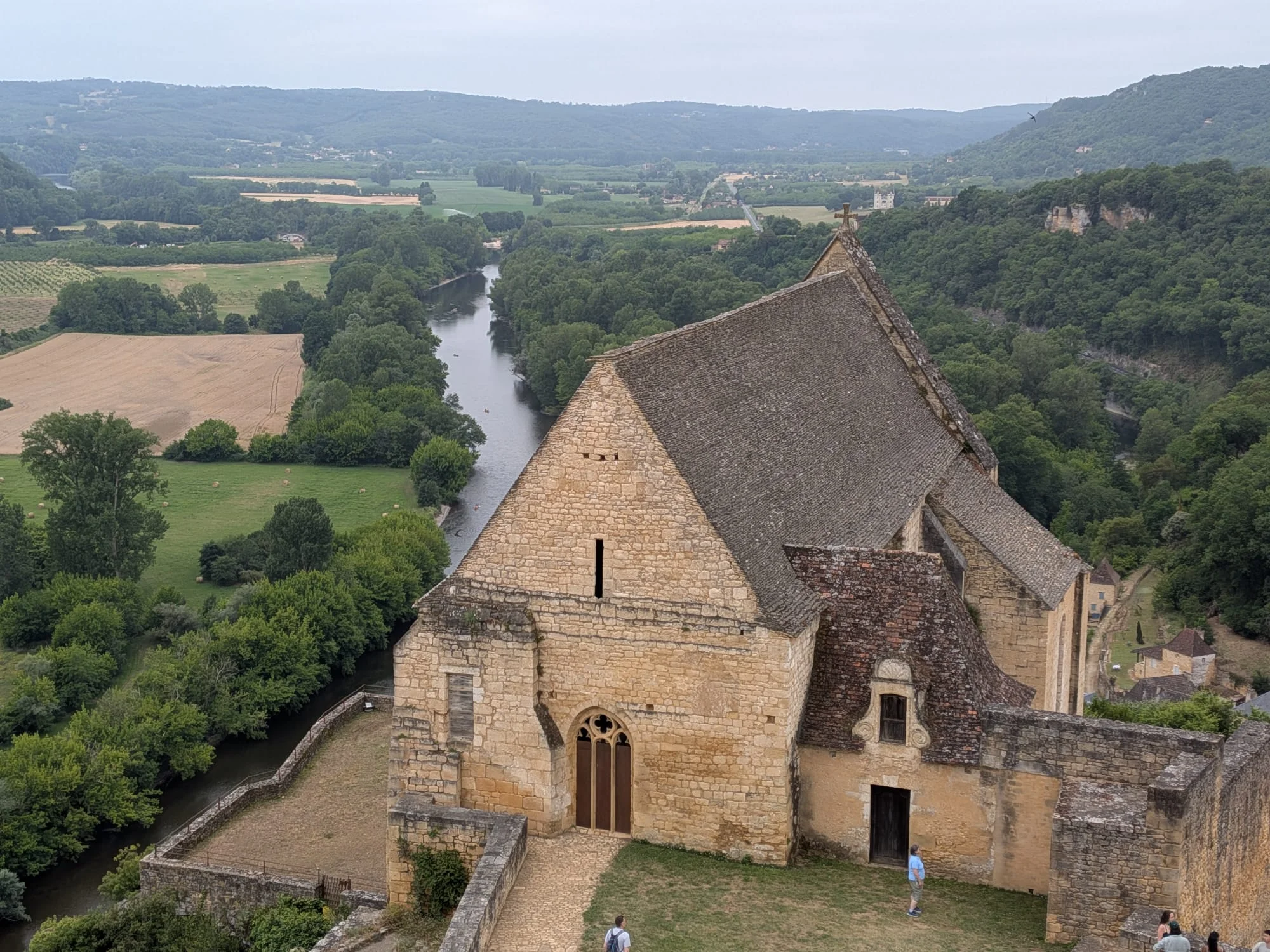Stone-tiled chapel roof at Château de Beynac with the Dordogne winding through the valley below