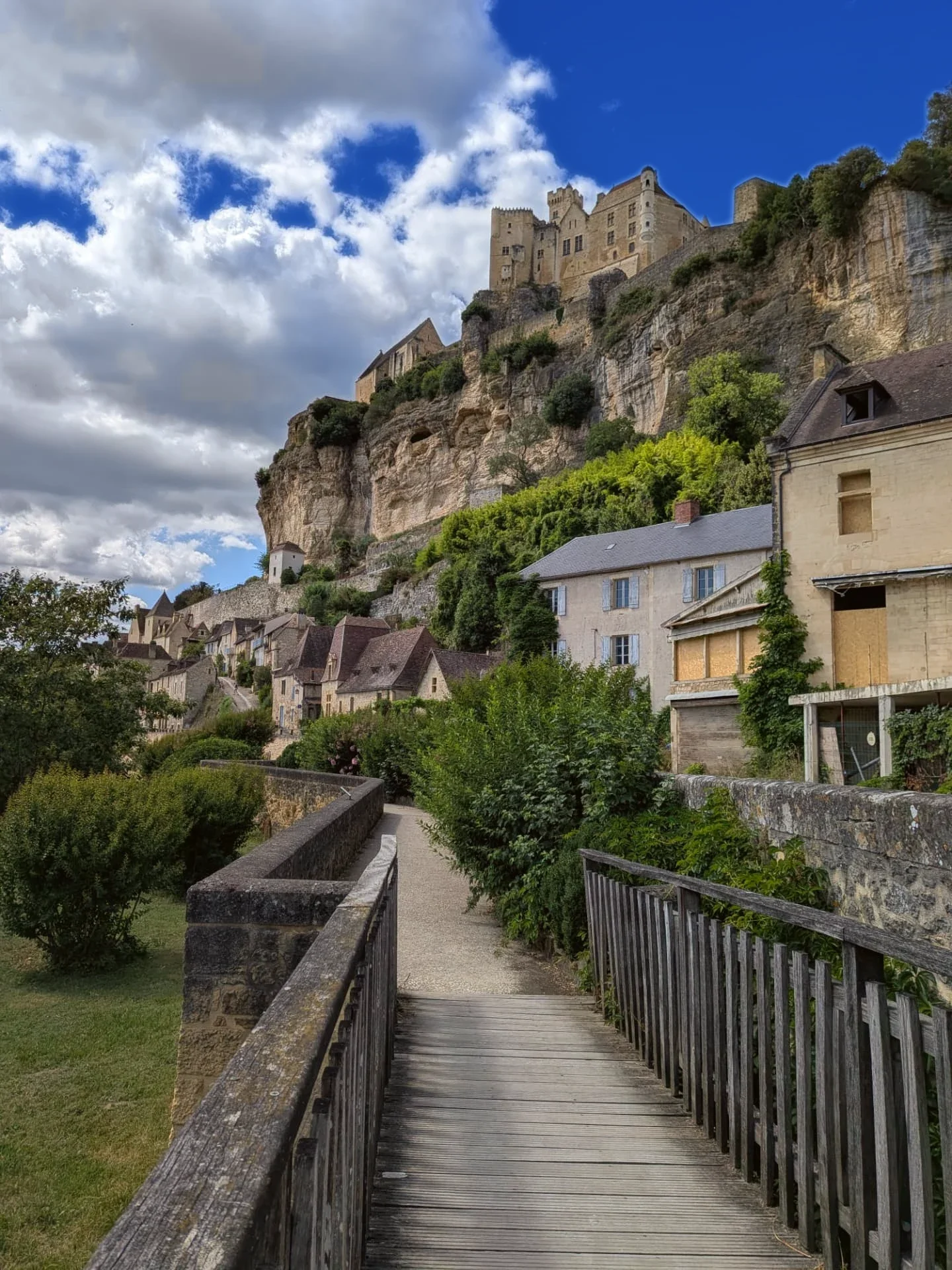 Wooden footbridge on the riverside path at Beynac, looking up to the château